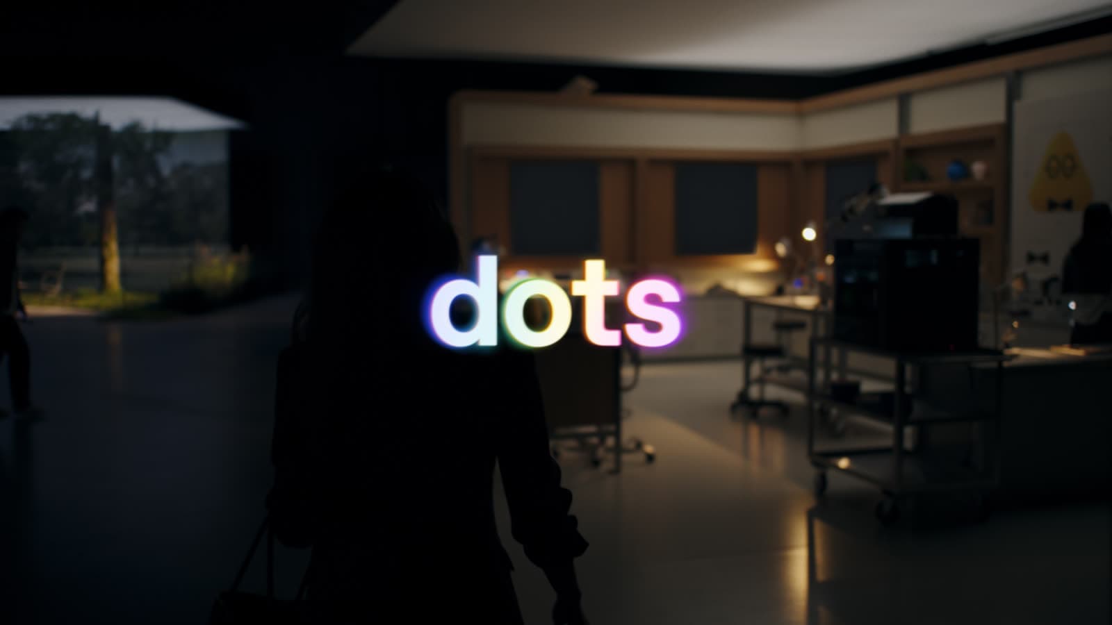 תמונת הפתיחה הרשמית של סרט ההשקה של Dots: המילה dots באותיות צבעוניות זוהרות על רקע מעבדה חשוכה, ודמות אישה בצללית בחזית