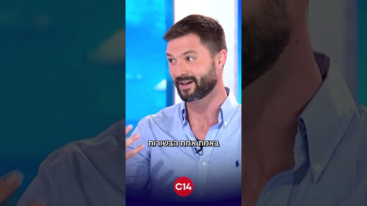 פריים מהקטע בערוץ 14: מקסים גומברג בחולצה תכלת באולפן, עם סמל C14