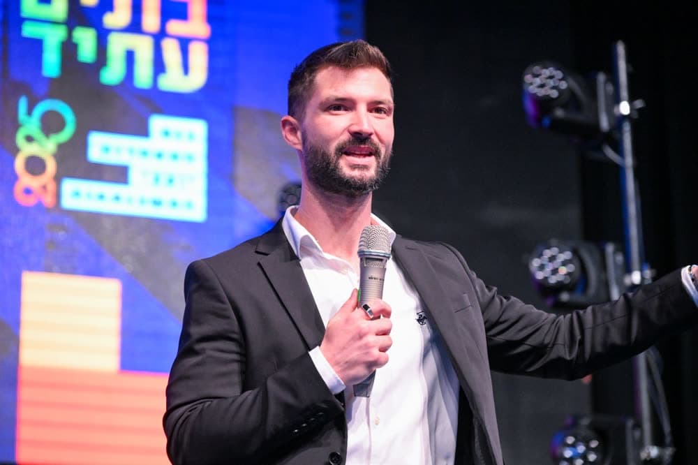 מקסים גומברג עם מיקרופון על במת ועידת ״בונים עתיד״